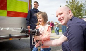 Child using fire hose with fireman