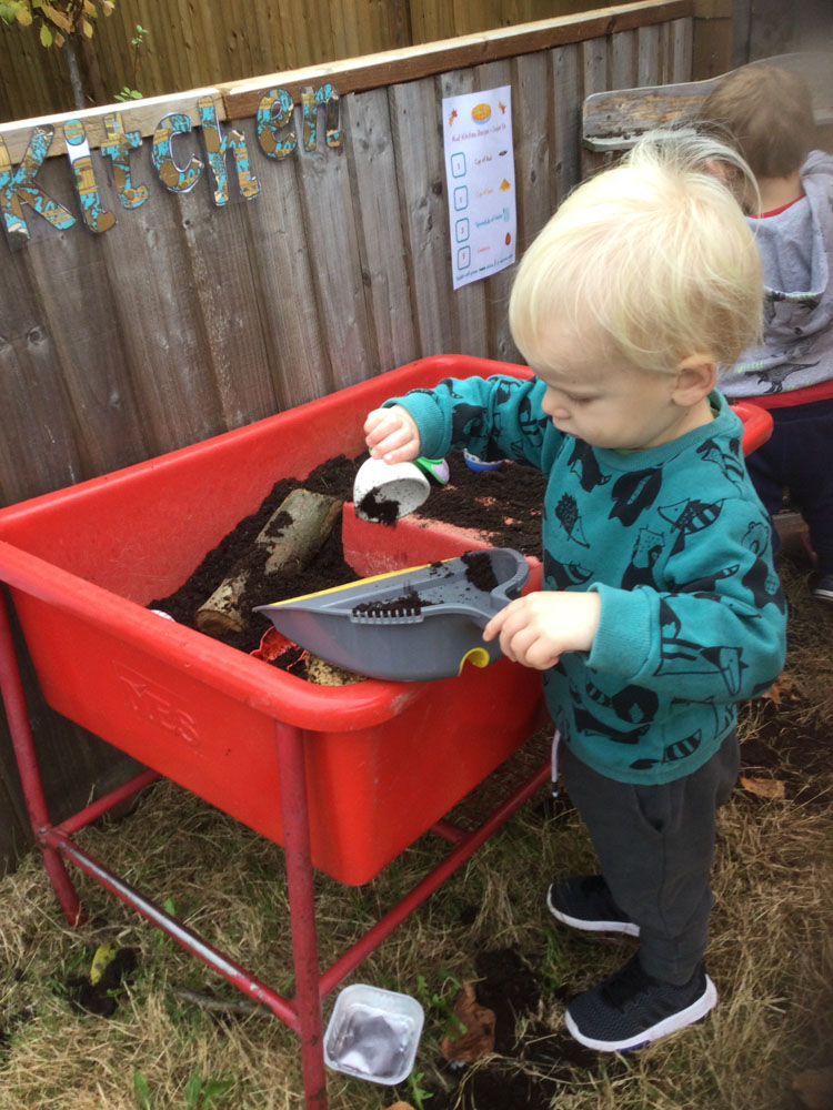 Child playing with dustpan and mud