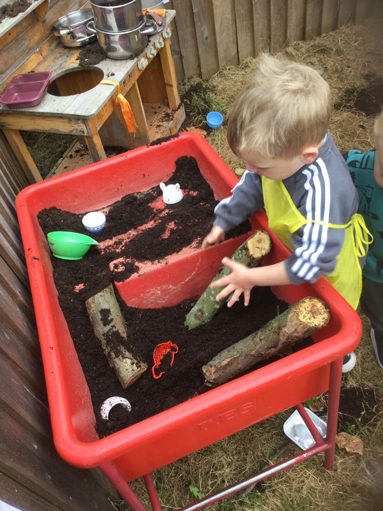 Child playing with mud and wood