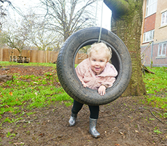 Child playing on a tire swing