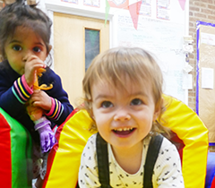 Child smiling at the camera, using soft play equipment