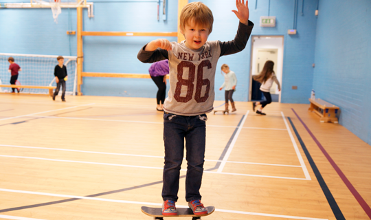 Children's Holiday Club kids playing on skateboards and other apparatus