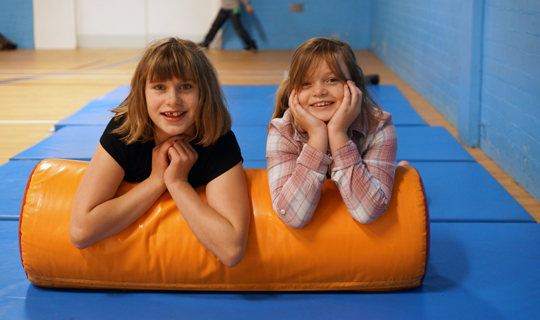 two young girls looking towards camera on soft play apparatus