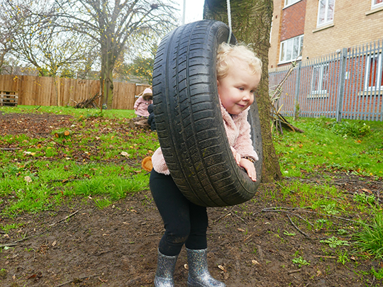 Child playing on tire swing