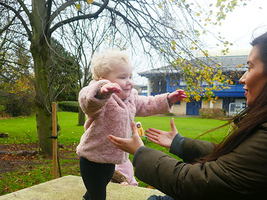 Child playing outdoors with nursery staff member